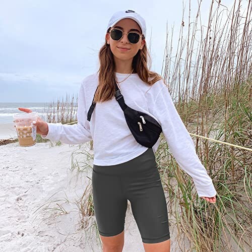Woman in casual attire with coffee on beach